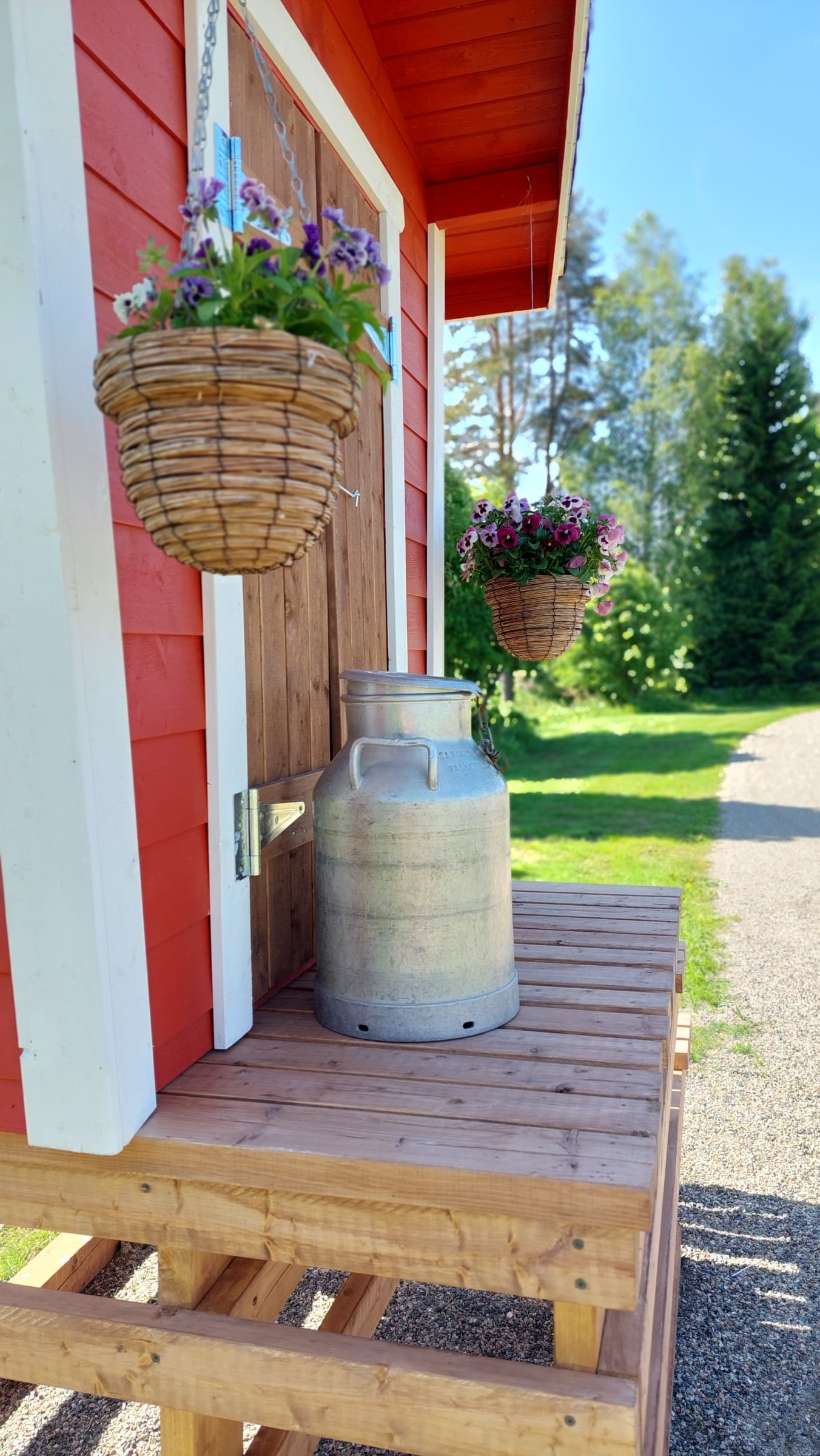 Virkistyspolun varrella oleva maitolaituri, jonka kannella maitotonkka ja kesäkukkia